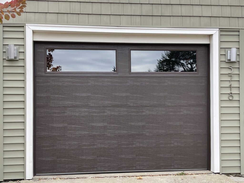 A modern dark brown garage door with two horizontal windows, installed by Max Garage Door in Minneapolis, MN.