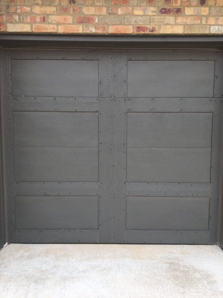 A modern dark grey garage door installed by Windsor Door, Siding & Window in Oklahoma City, OK.
