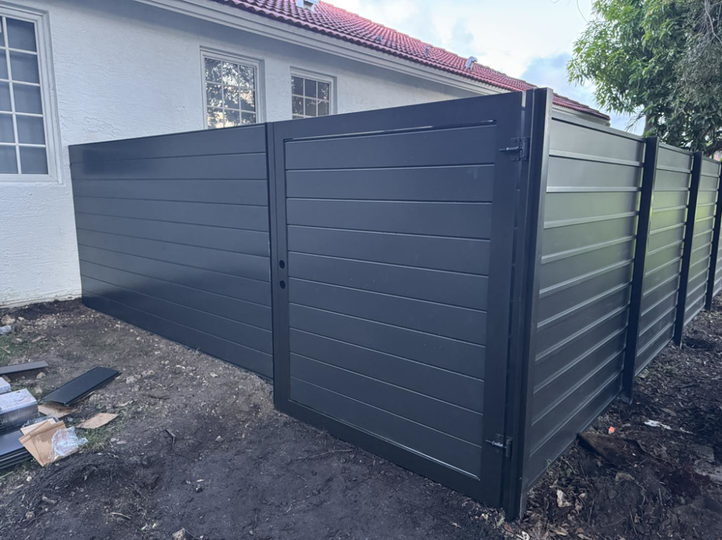 A modern dark grey horizontal slat fence with a gate installed next to a residential property by HD Multi Service USA INC in Miami, FL.