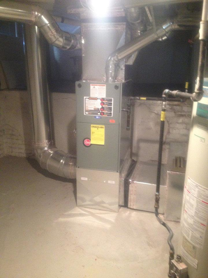 A modern furnace unit with extensive ductwork installed in a basement by Geddes Heating and Cooling in Aurora, CO.