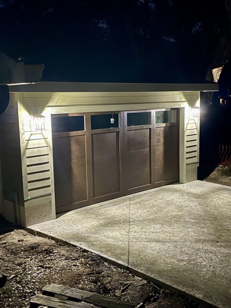 A modern garage door with horizontal panels, illuminated at night, installed by Precision Garage Door of Charleston in North Charleston, SC.