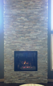 A modern gas fireplace integrated into a stylish stone wall, installed by North Central Service, Inc. in Minot, ND.