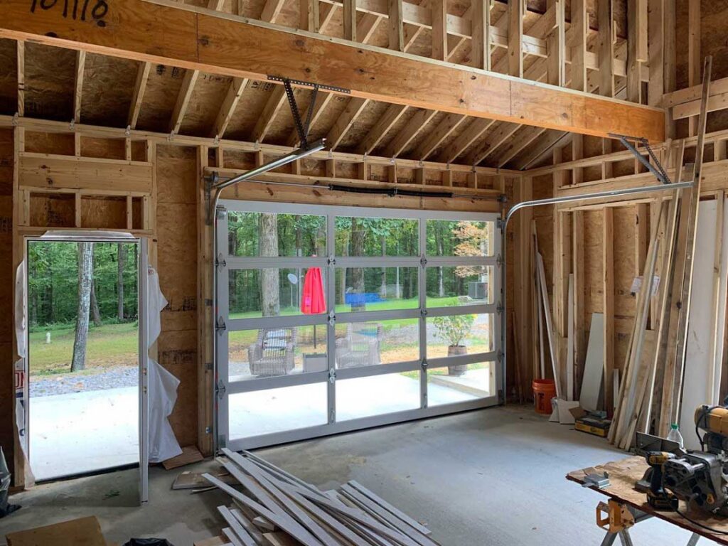 A modern glass garage door installed in a garage under construction by Rose Quality Garage Doors in Murfreesboro, TN