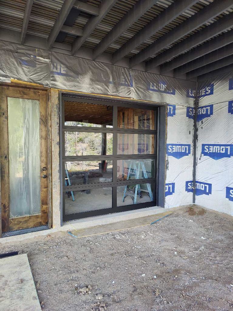 A modern glass garage door installation in progress on a new build, handled by JT's Overhead Doors in Gilbert, AZ.
