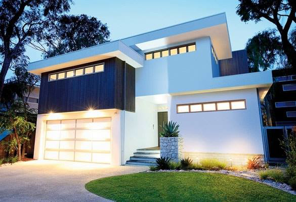 A modern house featuring a large, illuminated glass panel garage door installed by Birmingham Garage Doors Installation and Repair in Birmingham, AL