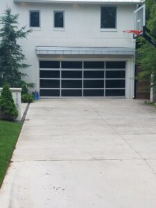 A modern glass panel garage door installed on a residential home by Garage Door Specialists Of Oklahoma Inc. in Midwest City, OK.