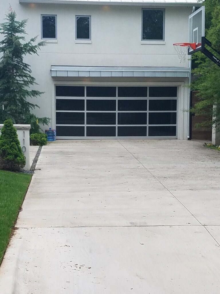 A modern glass panel garage door installed on a residential home by Garage Door Specialists Of Oklahoma Inc. in Midwest City, OK.