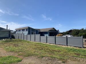 A modern grey composite fence installed along a property line by Faxon Fencing in Corvallis, OR.