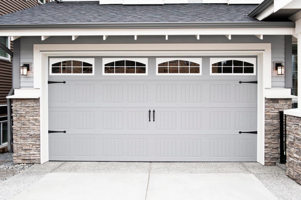 A modern grey garage door with decorative windows and hardware on a residential house by Hometown Garage Doors in Crestview, FL.