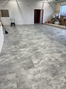 A large room showcasing a modern grey plank flooring installation by Keystone Carpet & Tile in Omaha, NE.