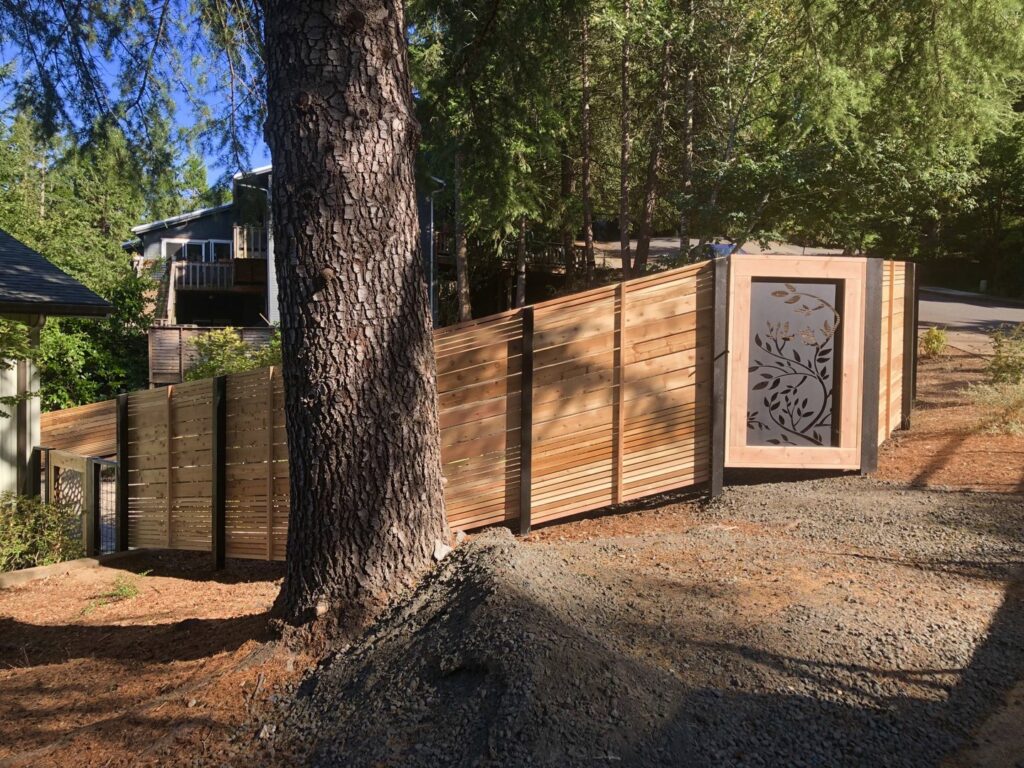 A modern horizontal slat fence with a decorative metal gate insert installed by Pacific Woods Fence and Deck in Springfield, OR.