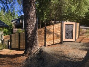 A modern horizontal slat fence with a decorative metal gate insert installed by Pacific Woods Fence and Deck in Springfield, OR.