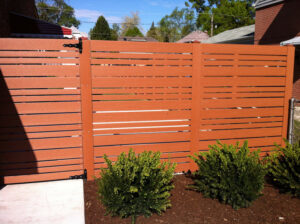 A modern horizontal slat fence in a reddish-brown finish installed by Freeman Fence in Atlanta, GA.
