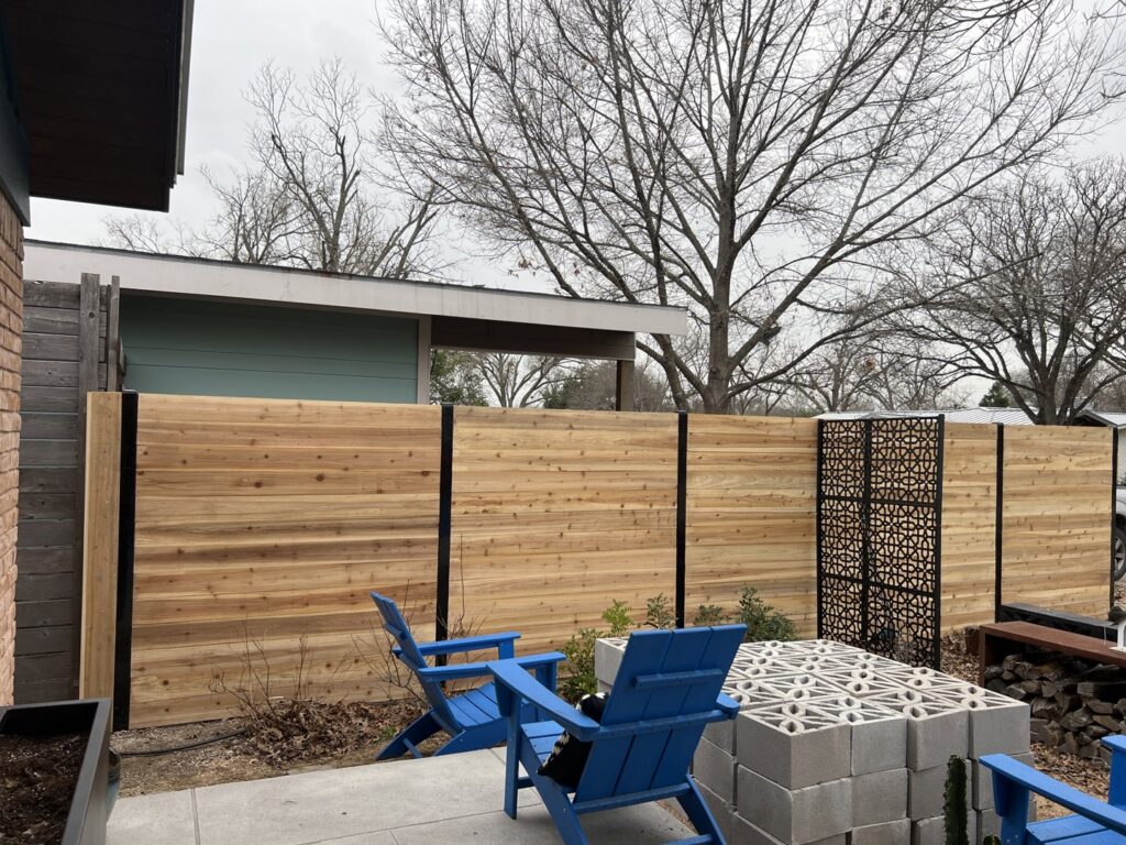 A modern horizontal slat fence with decorative metal panels installed by Good Neighbor Fencing and Construction in Austin, TX.