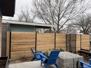 A modern horizontal slat fence with decorative metal panels installed by Good Neighbor Fencing and Construction in Austin, TX.