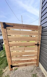 A modern horizontal slat wood fence gate installed next to a house by Central Ohio Fence in Newark, OH.