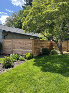 A modern horizontal slat wood fence installed in a residential yard by Howell Fence Inc. in Oregon City, OR.