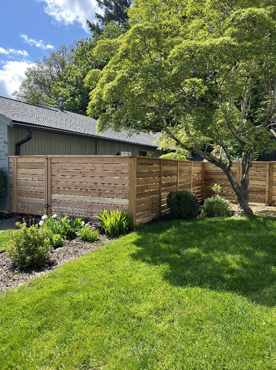 A modern horizontal slat wood fence installed in a residential yard by Howell Fence Inc. in Oregon City, OR.