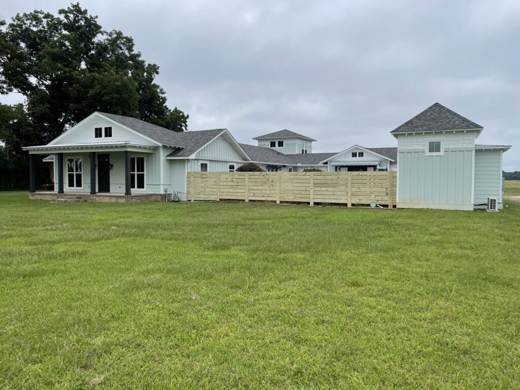 A modern horizontal slat wood fence installed around a contemporary home by Jaguar Fence LLC in Mobile, AL.