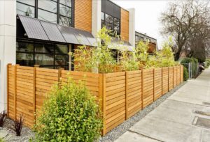 A modern horizontal slat wood fence installed along a sidewalk by Stand Strong Fencing of Plano, TX
