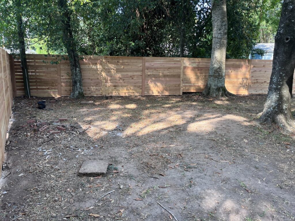 A modern horizontal slat wooden fence installed in a backyard by Dallas' Custom Carpentry in Alexandria, LA.