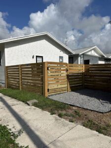 A modern horizontal slat wooden fence with a gate installed by Elite Fence and Outdoor of Tampa Bay in Tampa, FL.
