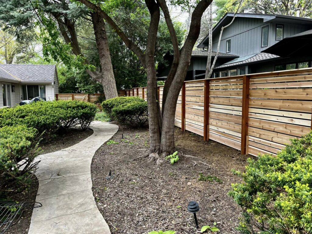 A modern horizontal wood fence installed around a residential property by Custom Vinyl Fabrication in Omaha, NE.