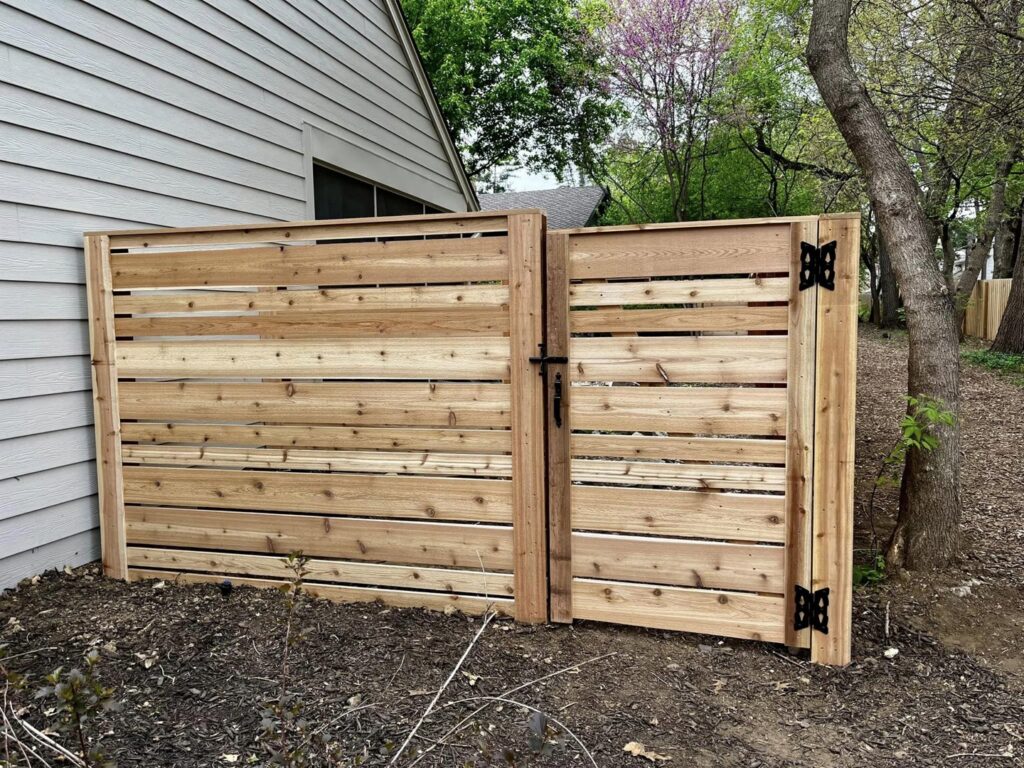 A modern horizontal wood fence with an integrated gate installed by Custom Vinyl Fabrication in Omaha, NE.