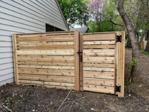 A modern horizontal wood fence with an integrated gate installed by Custom Vinyl Fabrication in Omaha, NE.