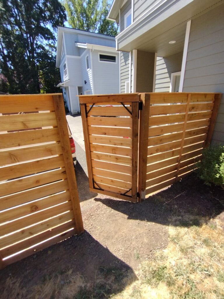 A modern horizontal slat wood fence with an integrated gate by Stewart & Son Gate & Fence Co. in Hillsboro, OR
