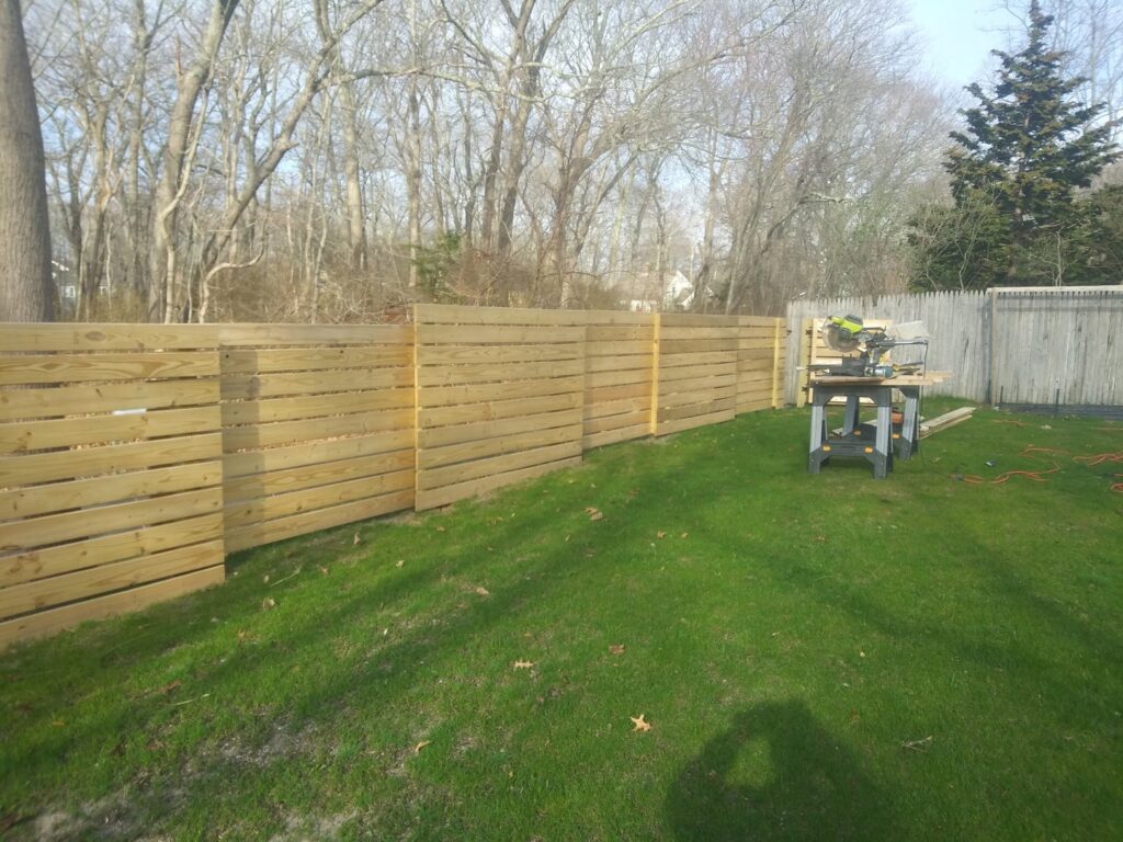 A modern horizontal slat wood fence being installed or newly completed by Reilly Fence Inc in Cranston, RI.