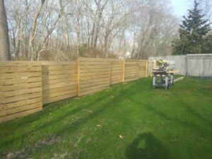 A modern horizontal slat wood fence being installed or newly completed by Reilly Fence Inc in Cranston, RI.