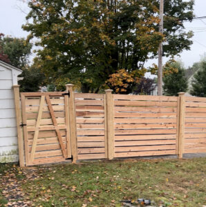 A modern horizontal wooden fence with a matching gate installed by White Eagle Fence Inc in New Haven, CT.