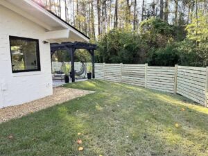 A modern horizontal wood slat fence enclosing a backyard patio area by Precision Fence in Meridian, MS.