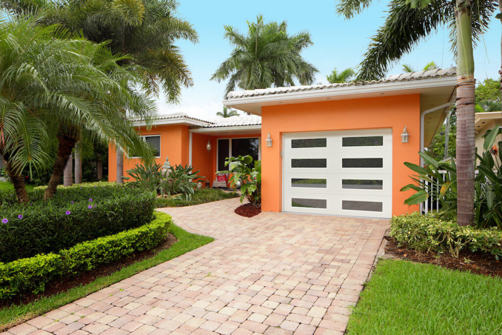 A modern house with an orange exterior and a white garage door with horizontal windows, installed by Precision Garage Door Service of Mobile in Mobile, AL.