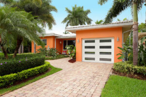 A modern house with an orange exterior and a white garage door with horizontal windows, installed by Precision Garage Door Service of Mobile in Mobile, AL.