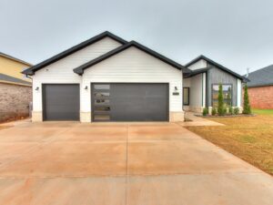 A modern house with two dark grey garage doors, one featuring horizontal windows, installed by CCM Overhead Doors in Oklahoma City, OK