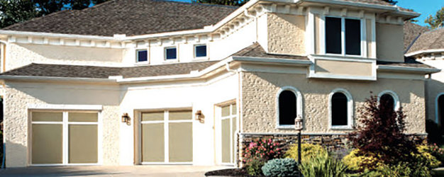 A modern house featuring two light-colored garage doors with frosted glass panels by Overhead Door Company of Knoxville in Knoxville, TN