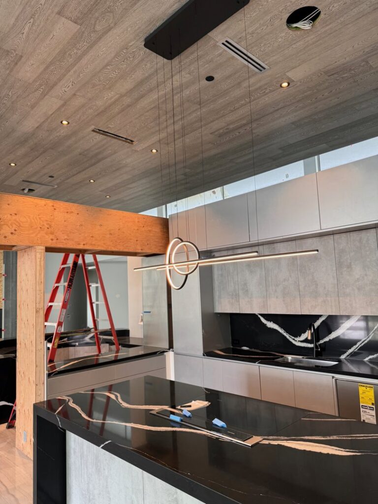 A modern light fixture being installed over a kitchen island, showcasing electrical work by Industrial Edge Electrical in Gilbert, AZ.