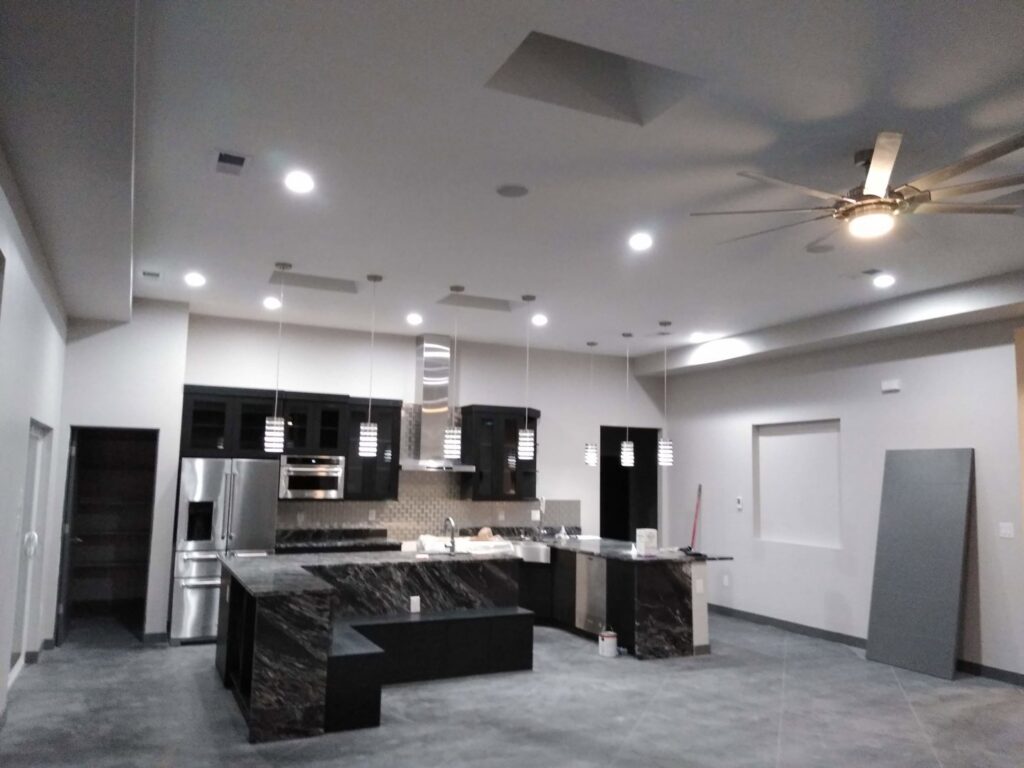 A modern kitchen featuring new recessed lighting, pendant lights, and a ceiling fan installed by The Specialist Electrical Contractor in Albuquerque, NM.