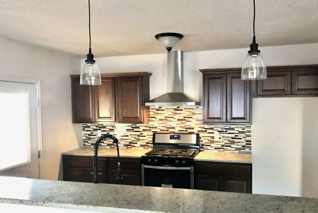 A modern kitchen featuring a newly installed range hood and gas stove by Home Repair Contractors in Las Cruces, NM