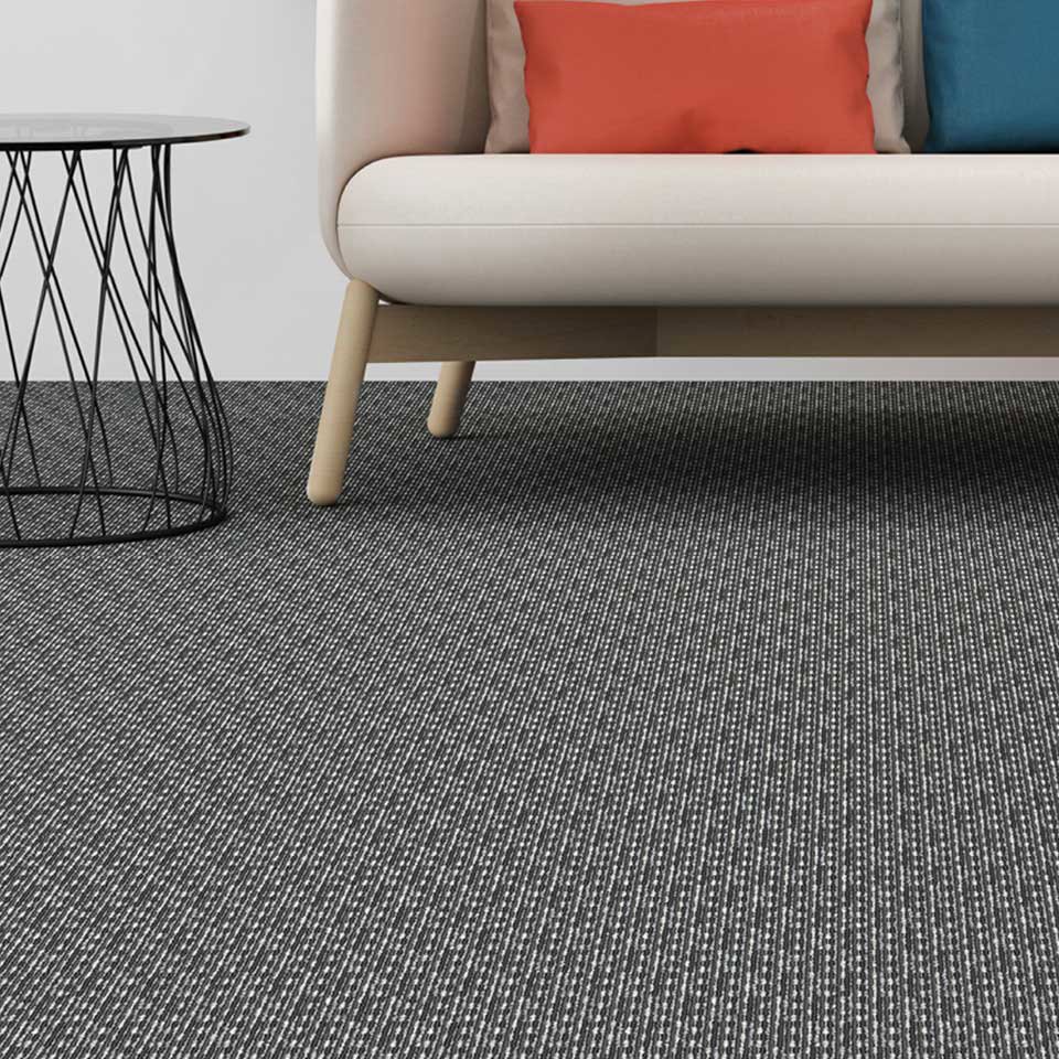 A modern living room featuring a stylish dark grey textured carpet installed by Eastpointe Interiors in Caledonia, MI.