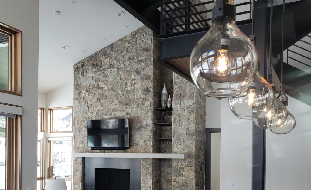 Modern living room with pendant lights, recessed lighting, and mounted TV installed by TBS Electric in West Jordan, UT.