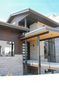 A modern outdoor wall sconce installed on the exterior of a contemporary home by ACJ Electric LLC in North Babylon, NY.