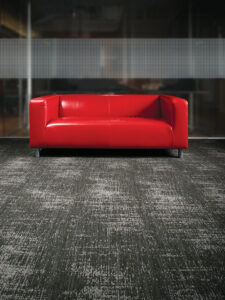 A modern patterned carpet installation with a red sofa, expertly completed by Flooring of Springfield in Springfield, IL.