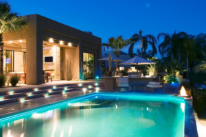 A modern swimming pool illuminated with stunning blue lighting at night, designed by Luxury Outdoors in Murfreesboro, TN.