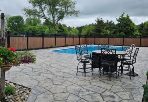 A modern privacy fence with wood-look panels and black metal enclosing a swimming pool area by Future Solutions Fence Supply in York, PA
