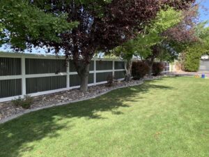 A modern privacy fence featuring dark vertical slats and white horizontal rails installed by Idaho Falls Fencing in Idaho Falls, ID.