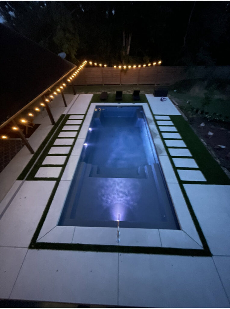 A modern rectangular swimming pool with integrated steps and stylish patio pavers by Central Pools, Inc. in Baton Rouge, LA
