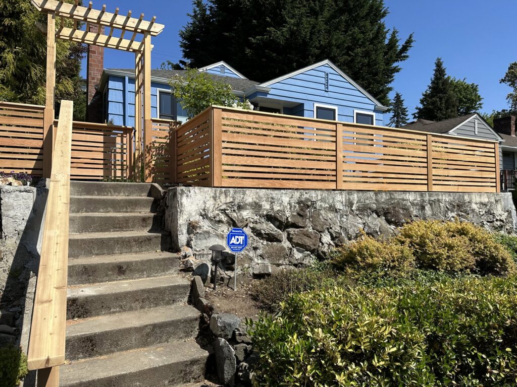 A modern horizontal slat fence with a stylish pergola gate entrance built by Helmco Fences in Seattle, WA.